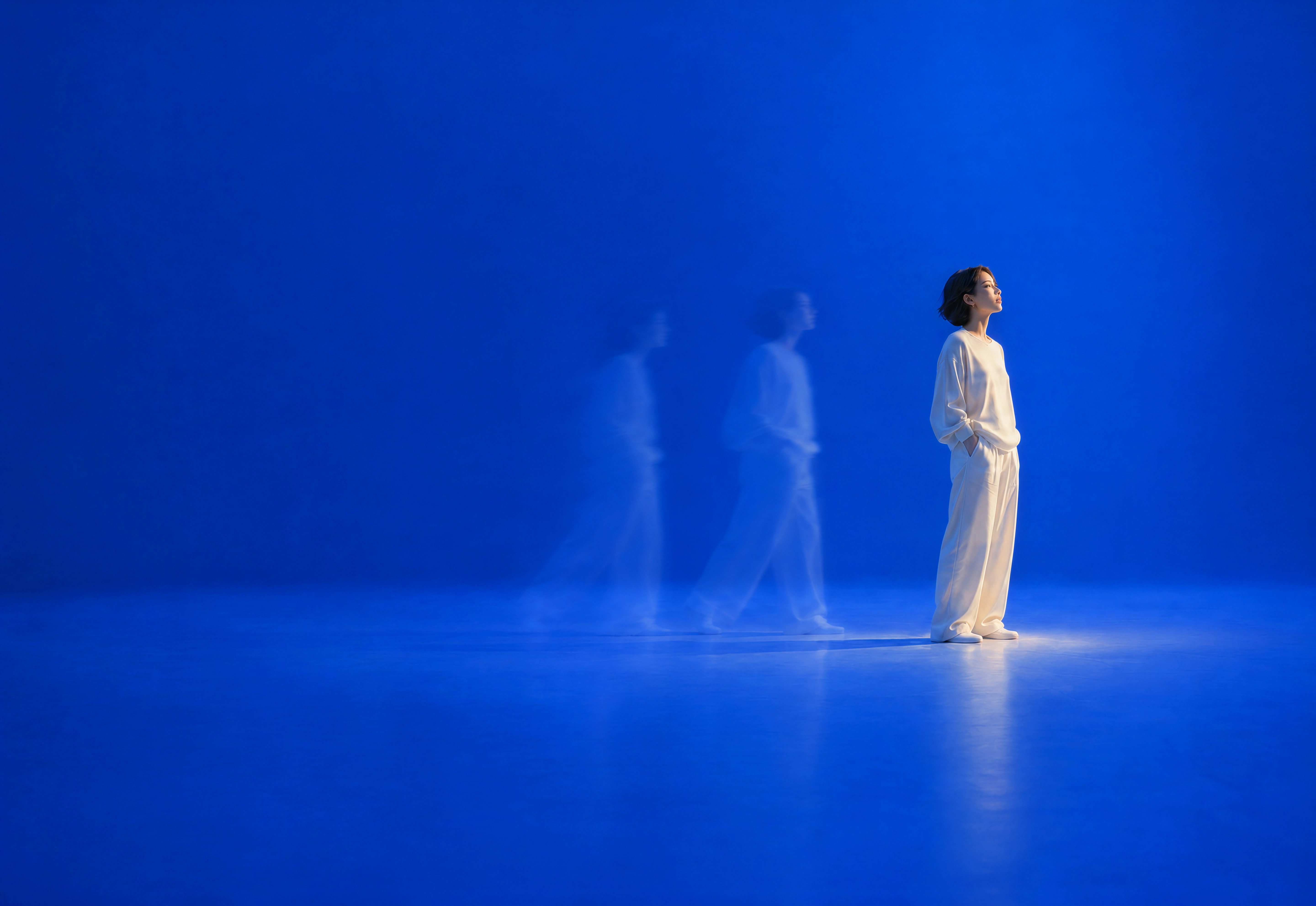 A woman in ivory stands at the end of a blue time-exposure portrait